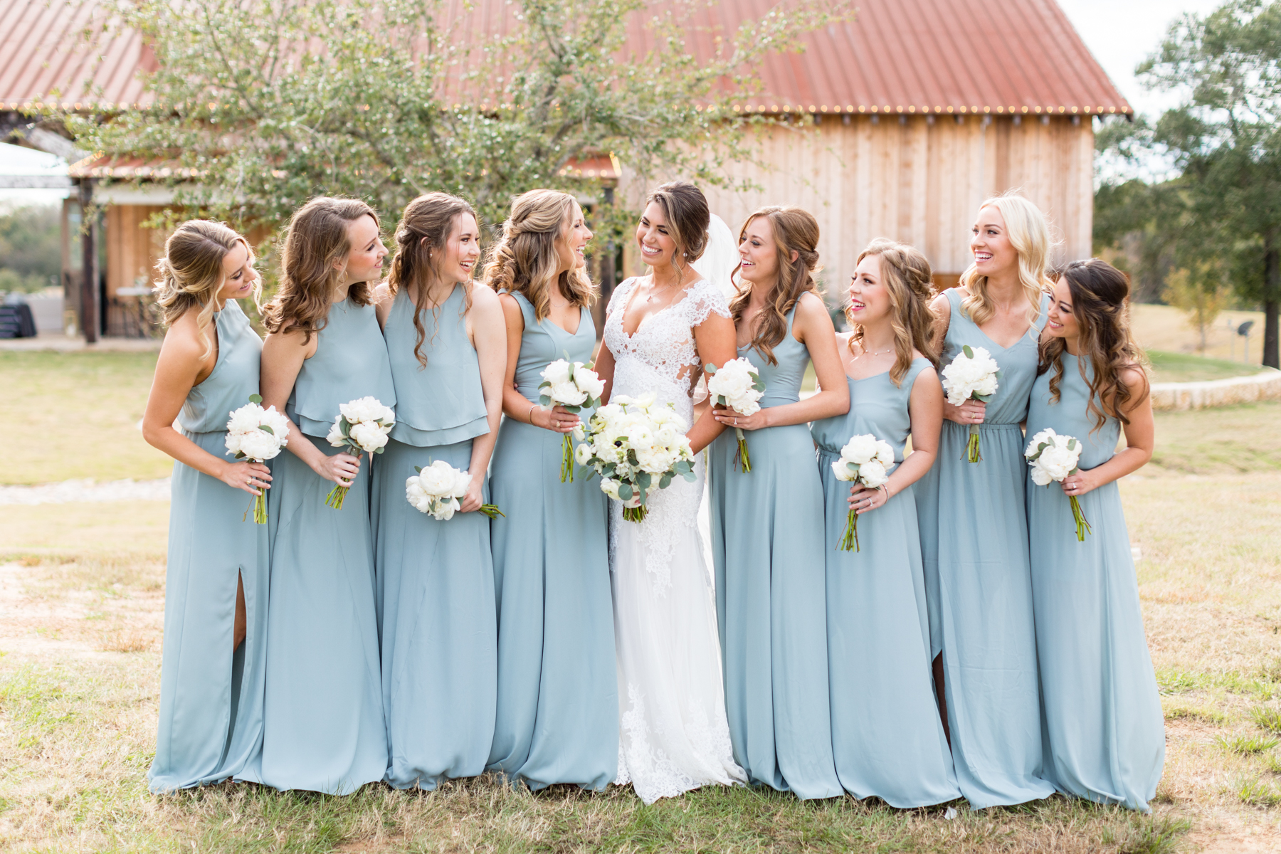 The bride and her wedding party in front of the reception barn at her family's ranch
