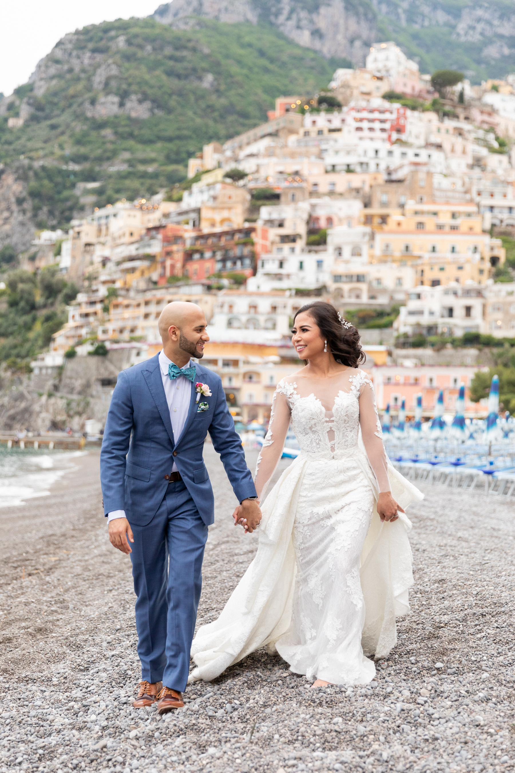 bride and groom walk on the beach in Positano, Italy